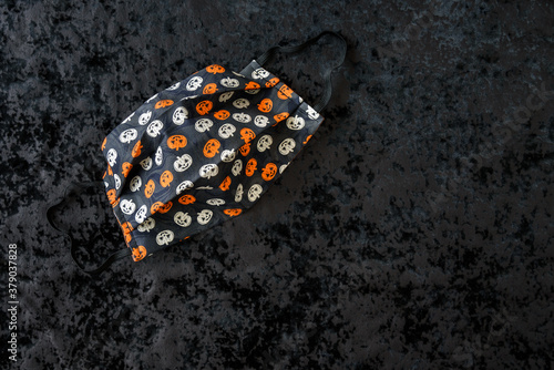 Orange and cream colored pumpkin patterned fabric face mask on a black background 