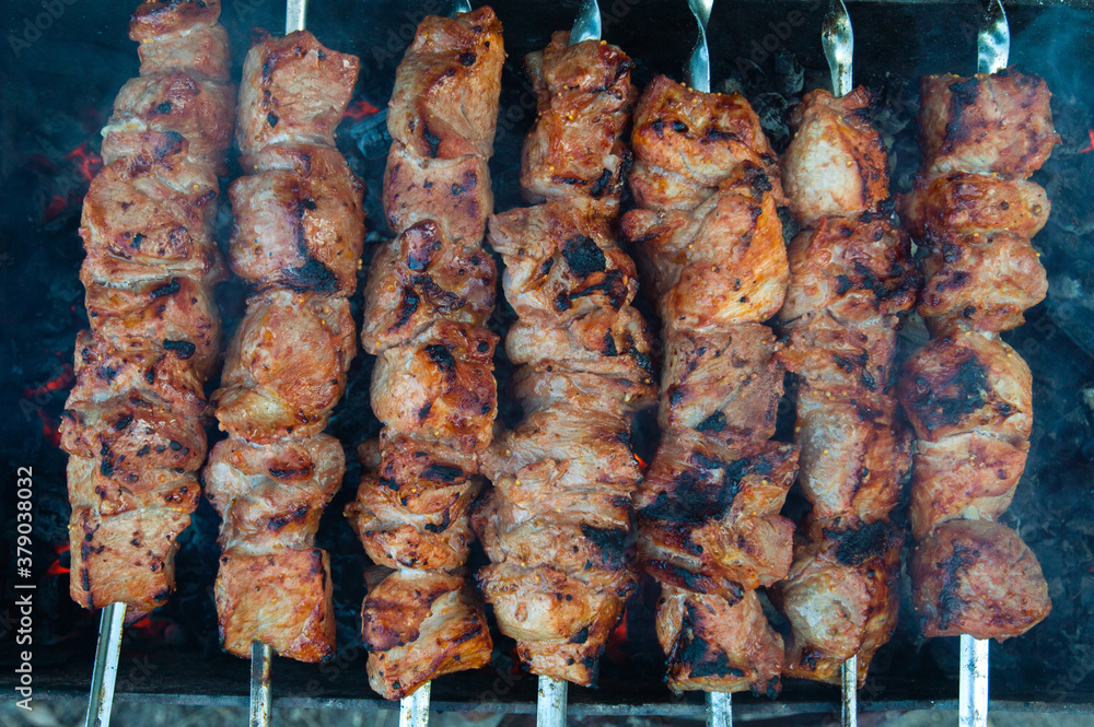 pork kebab on skewers is grilled over charcoal, smoke over a barbecue, the last degree of cooking, close