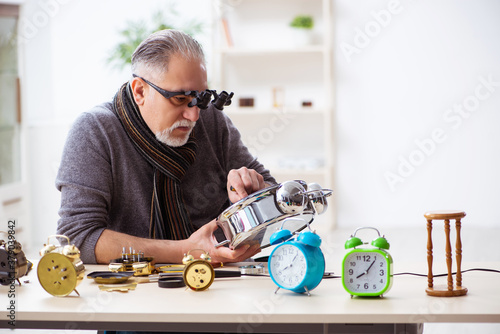 Fotografija Old male watchmaker working in the workshop