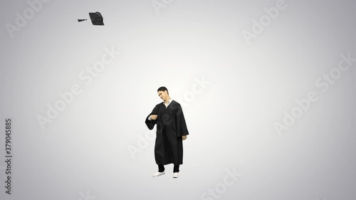 Male graduate throwing his mortarboard looking at camera, doing handsprings, dancing break dance and walking away on gradient background. photo