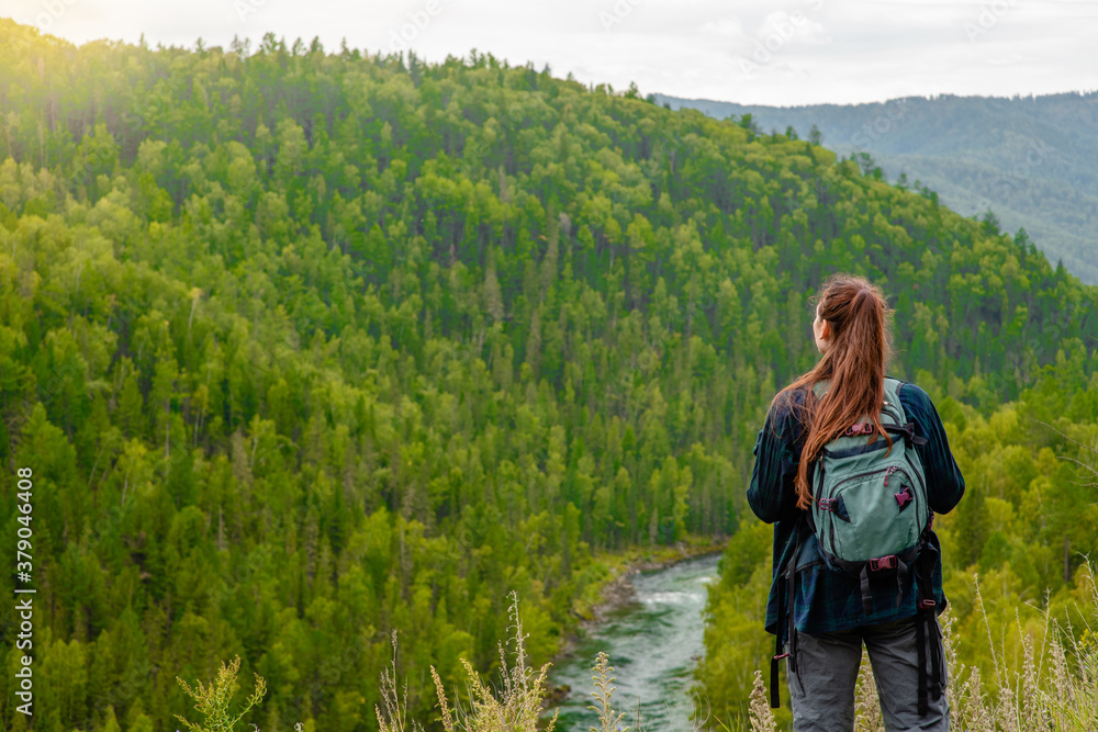 Young woman with backpack enjoys the view of nature at hike. Empty space for text
