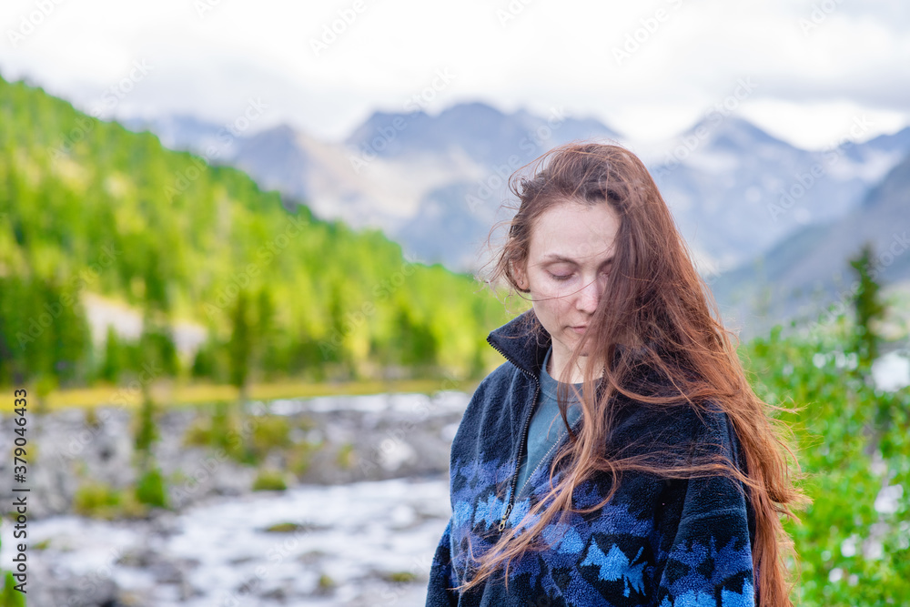 Portrait of a beautiful woman with long hair on the background of mountains and multinsky lake