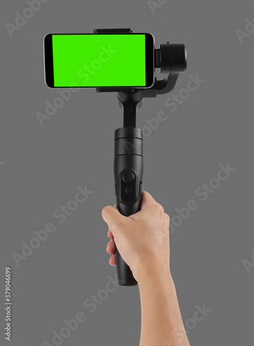 Man filming with a blank screen smartphone using a gimbal stabilizer, isolated on gray background
