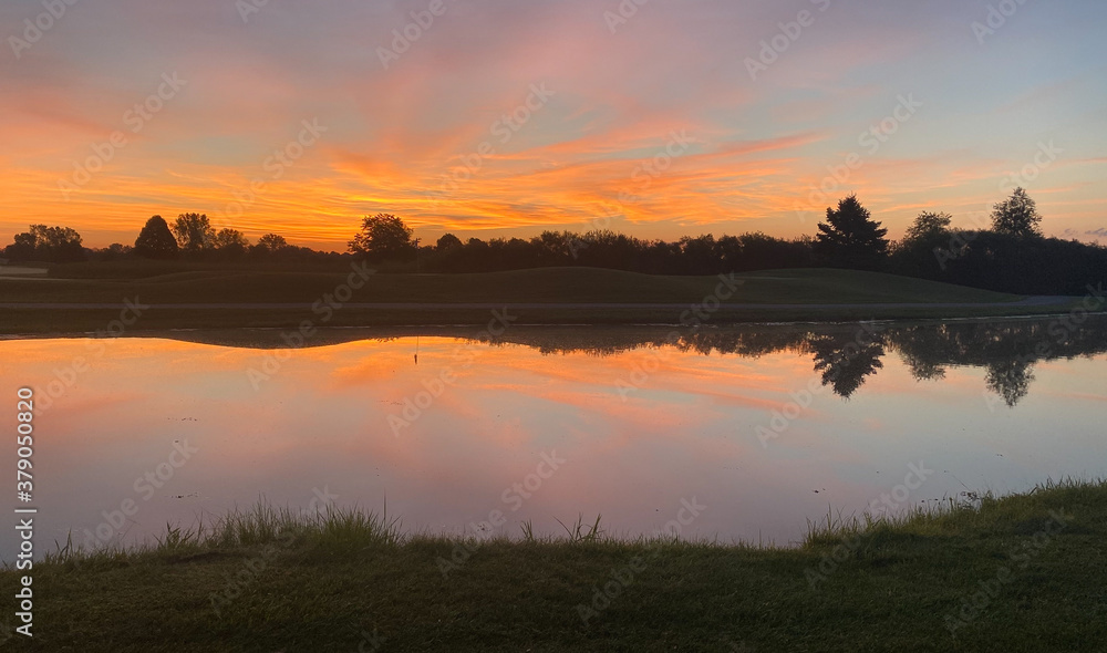 sunrise over golf course tree land silhouettes pond reflections