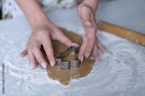 A girl cuts out cookies in the shape of a Christmas tree on the dough.