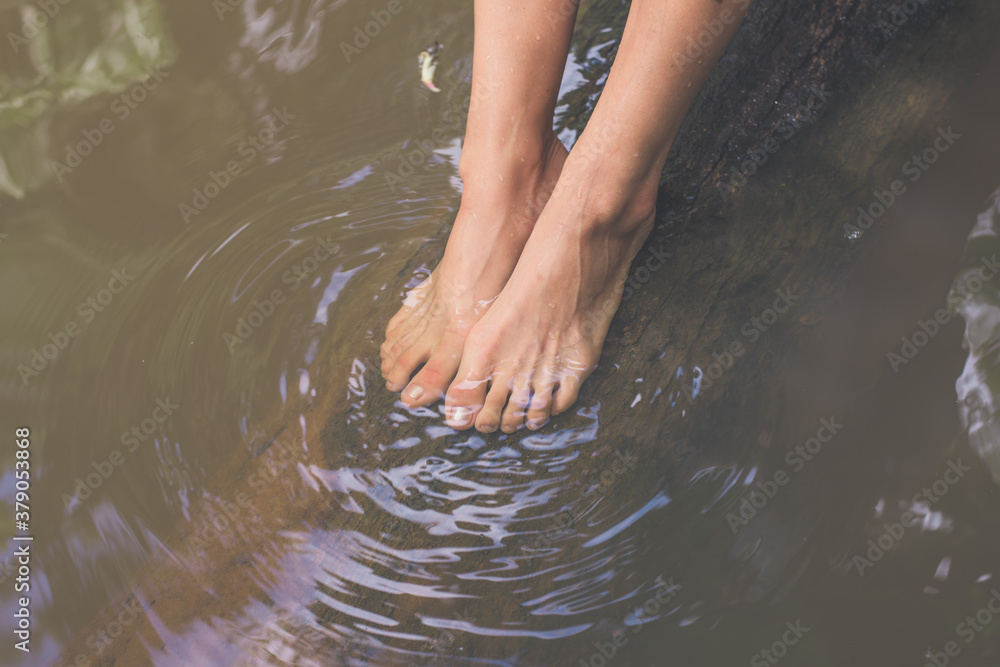 Feet of young girl underwater on a tree trunk