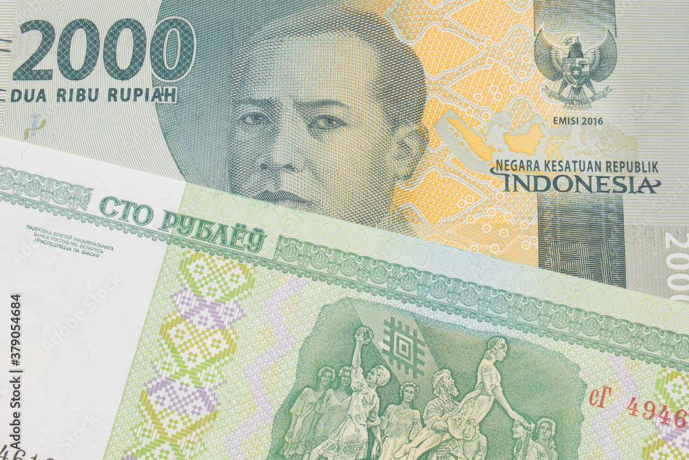 A macro image of a grey two thousand Indonesian rupiah bank note paired up with a green one hundred ruble note from Belarus.  Shot close up in macro.