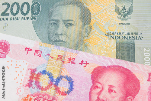 A macro image of a grey two thousand Indonesian rupiah bank note paired up with a red, one hundred yuan bank note from China.  Shot close up in macro.