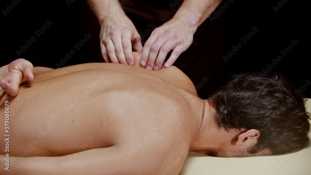 Chiropractic session in the studio - a therapist massaging the blade of his male client Chiropractic session in the studio - a therapist massaging the blade of his male client