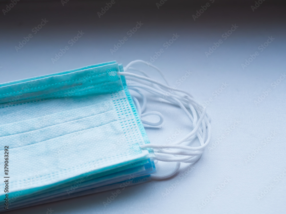 Blue surgical mask with rubber ear straps. Typical three-layer surgical mask for covering the mouth and nose. (Clipping path). Protection concept Blue surgical mask with rubber ear straps. Typical three-layer surgical mask for covering the mouth and nose. (Clipping path). Protection concept