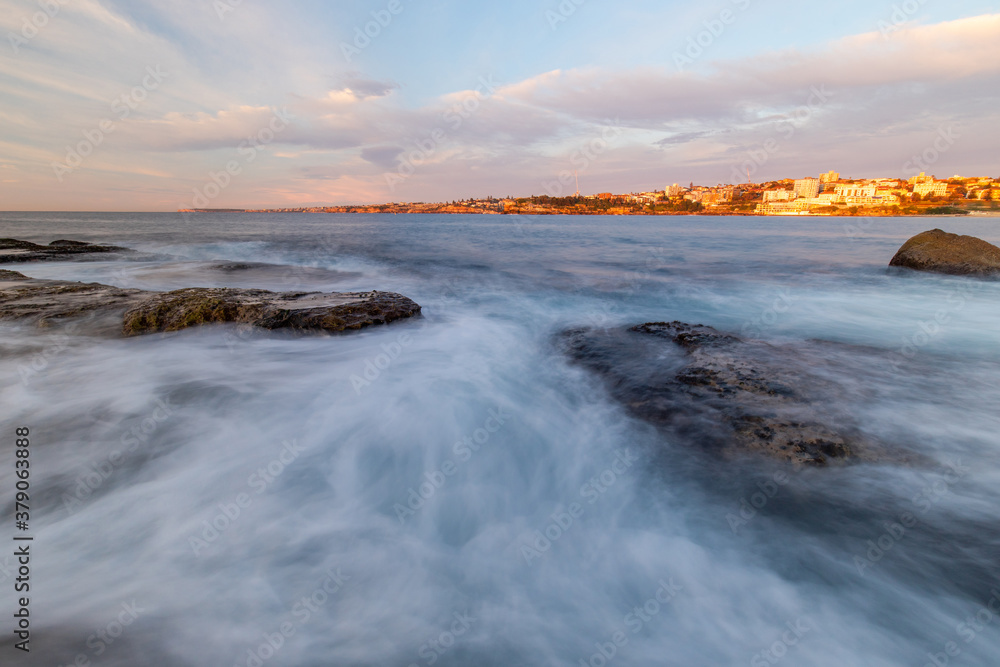 Fototapeta premium Rocky coastline with sea water flowing under the cloudy sky.