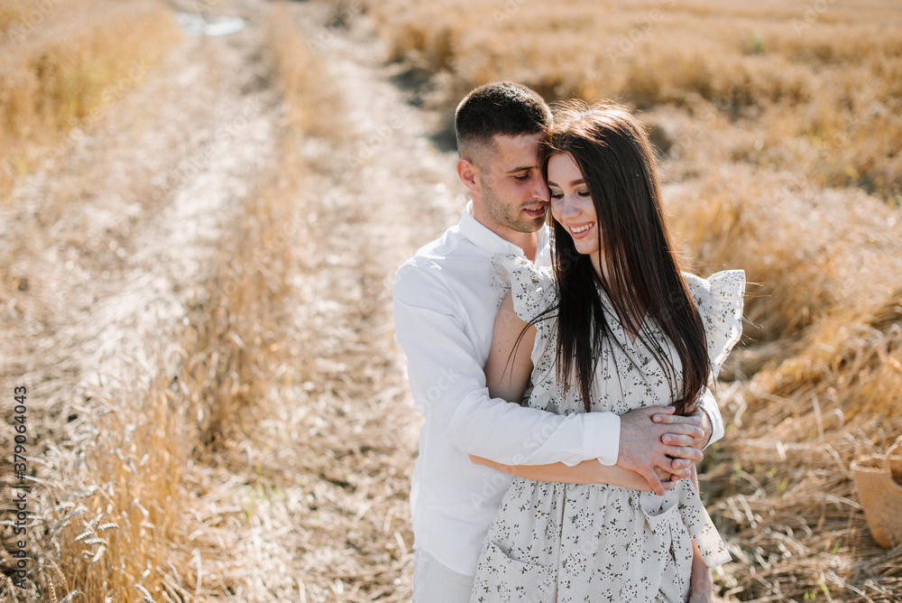 Young couple in the wheat field on sunny summer day. Couple in love have fun in golden field. Romantic couple in casual clothe outdoodrs on boundless field Young couple in the wheat field on sunny summer day. Couple in love have fun in golden field. Romantic couple in casual clothe outdoodrs on boundless field