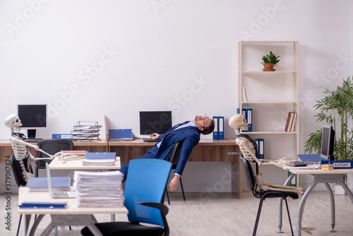 Wallpaper Mural Young male employee with skeletons in the office Torontodigital.ca