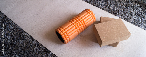 Orange foam roller and two yoga blocks on a beige mat photo