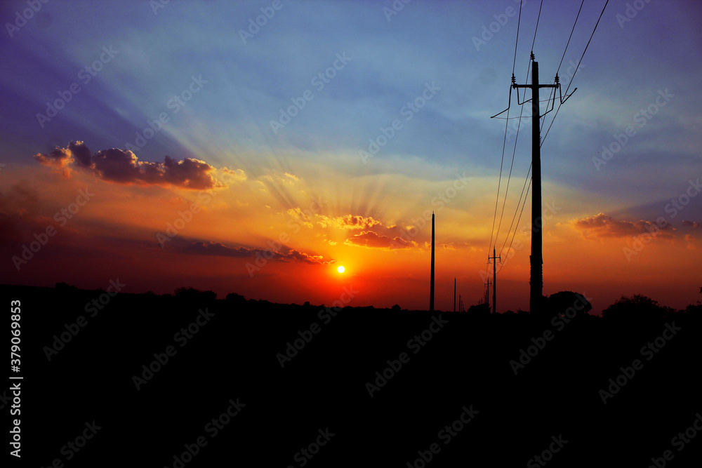 its and sunset image with electricity wire and poles and blue sky