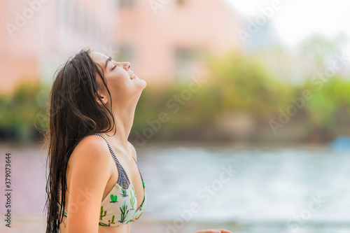 Young woman enjoying a sun in the luxury pool. Enjoying life. Vacations, holidays, having summer fun concept.
