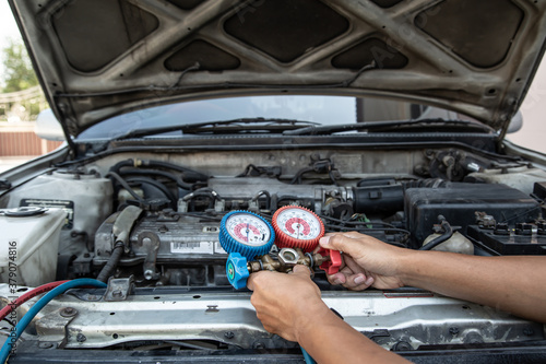 Auto mechanic are using measuring equipment tool for filling car air conditioners. Concepts of car care fix checking repair service and insurance.