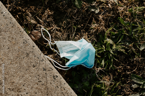 A used surgical mask littered as rubbish in a garden during the corona COVID-19 pandemic