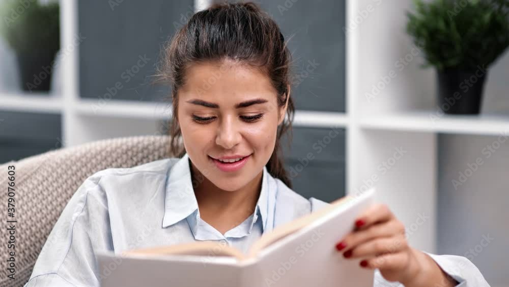 Happy mixed race woman reading interesting book on couch. Medium close up shot on 4k RED camera Happy mixed race woman reading interesting book on couch. Medium close up shot on 4k RED camera