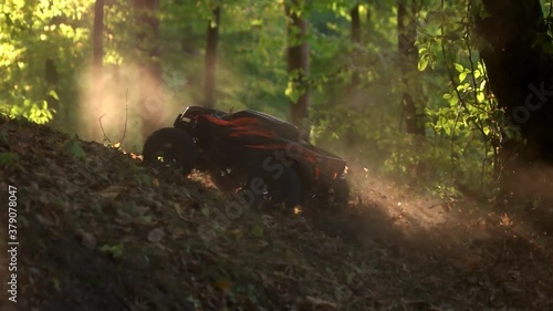 RC monster truck rides on dry leaves. Offroad race comprtition in a forest. Radio controlled car in woods. photo