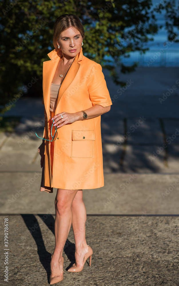 Woman in orange coat at street, woman outfit. Fancy style for ladies, autumn colors and fashion 