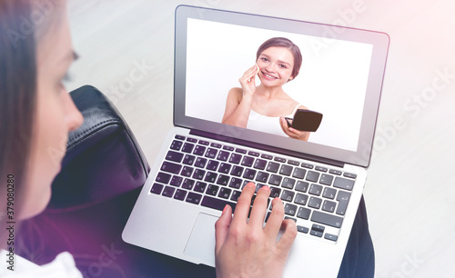 Young woman watching makeup tutorial on laptop