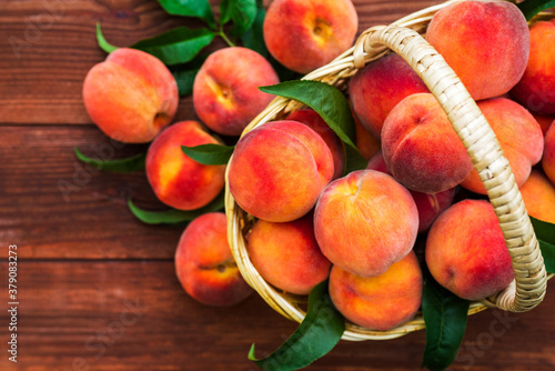 Canvas Print Freshly picked peaches in basket on a brown wooden background