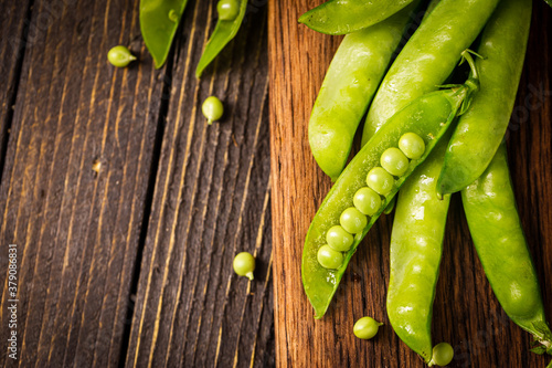 Pods of green peas on a old wooden background close up, soft focus