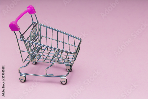 Empty trolley on soft pink background, buy and sell concept.