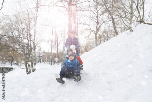 Children in the park in winter. Kids play with snow on the playground. They sculpt snowmen and slide down the hills. © alexkich