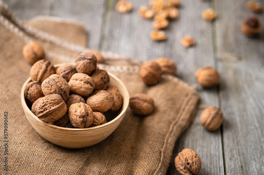 Whole walnuts in a bowl and jute bag on rustic old wooden table. Healthy organic food, BIO viands, natural background. Copy space for your advertising text message Whole walnuts in a bowl and jute bag on rustic old wooden table. Healthy organic food, BIO viands, natural background. Copy space for your advertising text message
