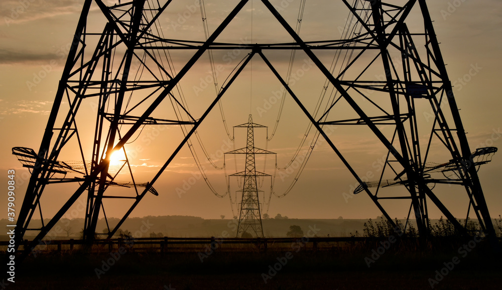 National grid electricity pylon framing distant pylons at sunrise.