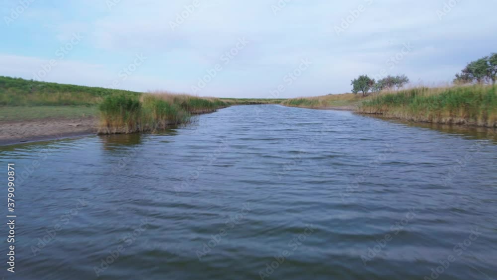 Shooting from drone flying low over the water surface, ducks swim in river, trees, reeds and dried grass grow along banks. Rural landscape with steppe expanses in the countryside. Shooting from drone flying low over the water surface, ducks swim in river, trees, reeds and dried grass grow along banks. Rural landscape with steppe expanses in the countryside.