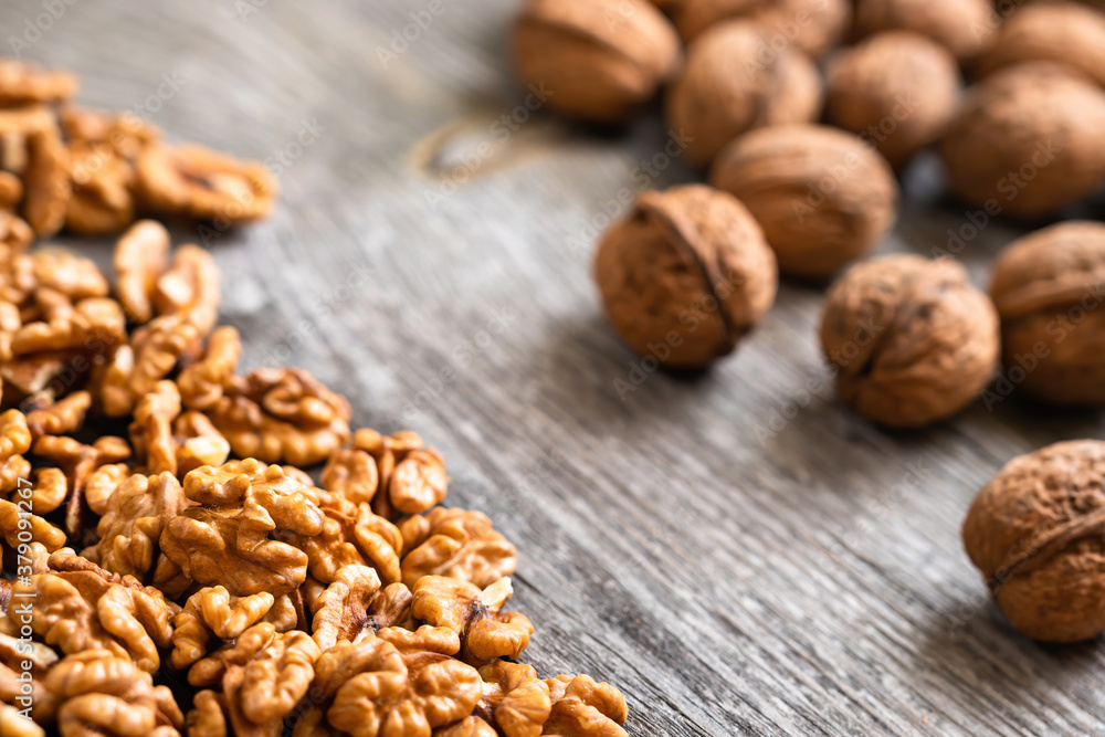 Heap of fresh walnut kernels and whole walnuts on wooden table - natural pattern background detail. Close up of brown surface texture. Healthy organic food, BIO viands, back to nature concept Heap of fresh walnut kernels and whole walnuts on wooden table - natural pattern background detail. Close up of brown surface texture. Healthy organic food, BIO viands, back to nature concept