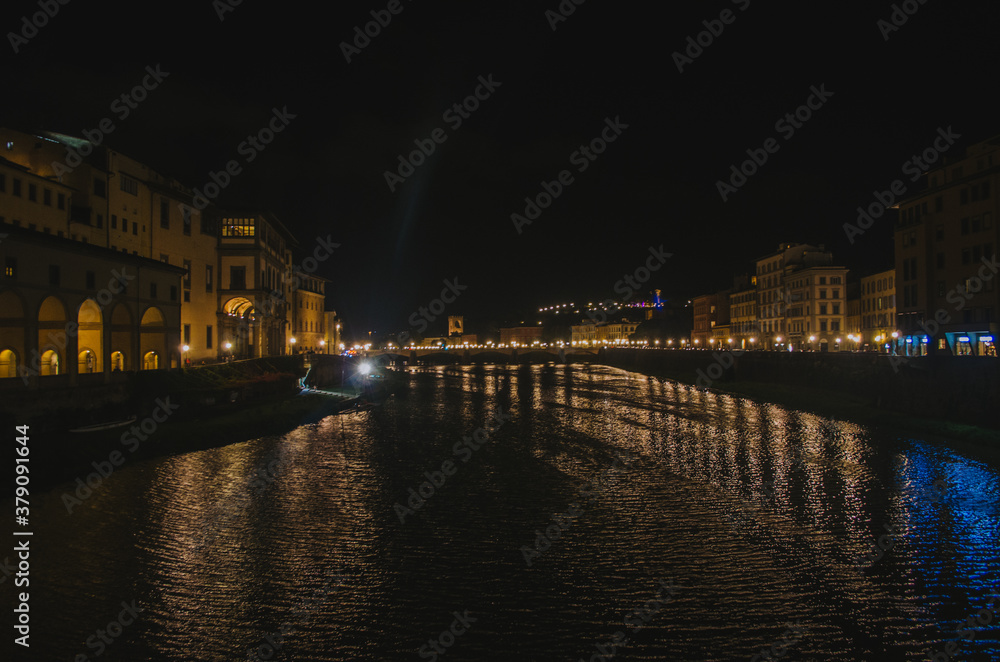 Rome, Italy - A panoramic view of Ponte Vecchio and the Arno river reflecting the buildings in its water during a illuminated and romantic evening.