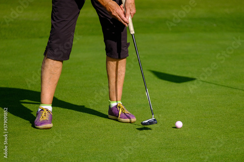 close up of feet of female senior golfer putting on green
