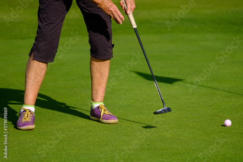 close up of feet of female senior golfer putting on green