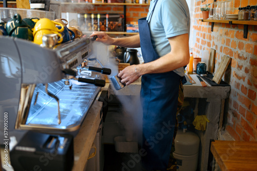 Male barista in apron prepares aroma coffee