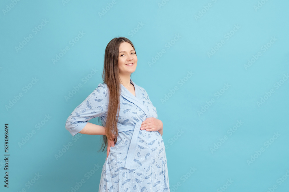 young happy pregnant woman on blue background in blue home bathrobe young happy pregnant woman on blue background in blue home bathrobe