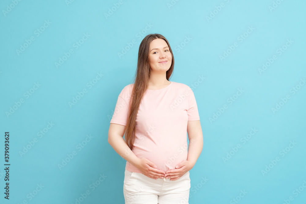 happy young pregnant woman in pink t-shirt on blue background happy young pregnant woman in pink t-shirt on blue background