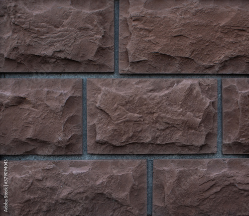 texture of brown rough textured blocks of the building facade; decorative background for design