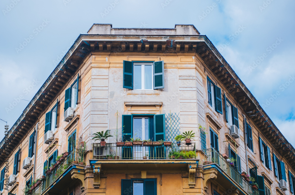 Rome, Italy - A beautifully architectured apartment in downtown Rome during a cloudy afternoon with the classical green windows and outdoor plants positioned below the windows