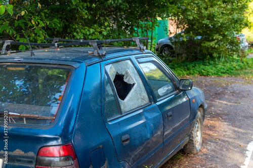 Car with broken rear door glass on the side of a country road. Consequence of crime, theft © Андрей Киселев