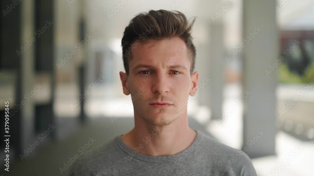 Portrait of a serious handsome man looking at the camera against a blurred background of a city street. Close-up of the face of an attractive Caucasian guy. Slow motion Portrait of a serious handsome man looking at the camera against a blurred background of a city street. Close-up of the face of an attractive Caucasian guy. Slow motion