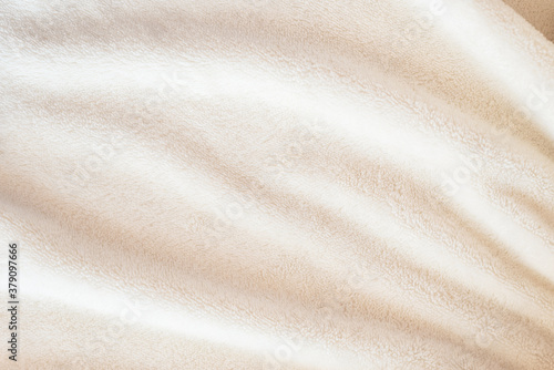 A soft cozy plaid made of white fabric with a pile lies in beautiful folds