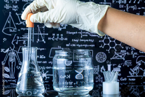 chemist dropping the clear reagent into test tube for reaction testing in chemical laboratory, with chemical equations and periodic table background.