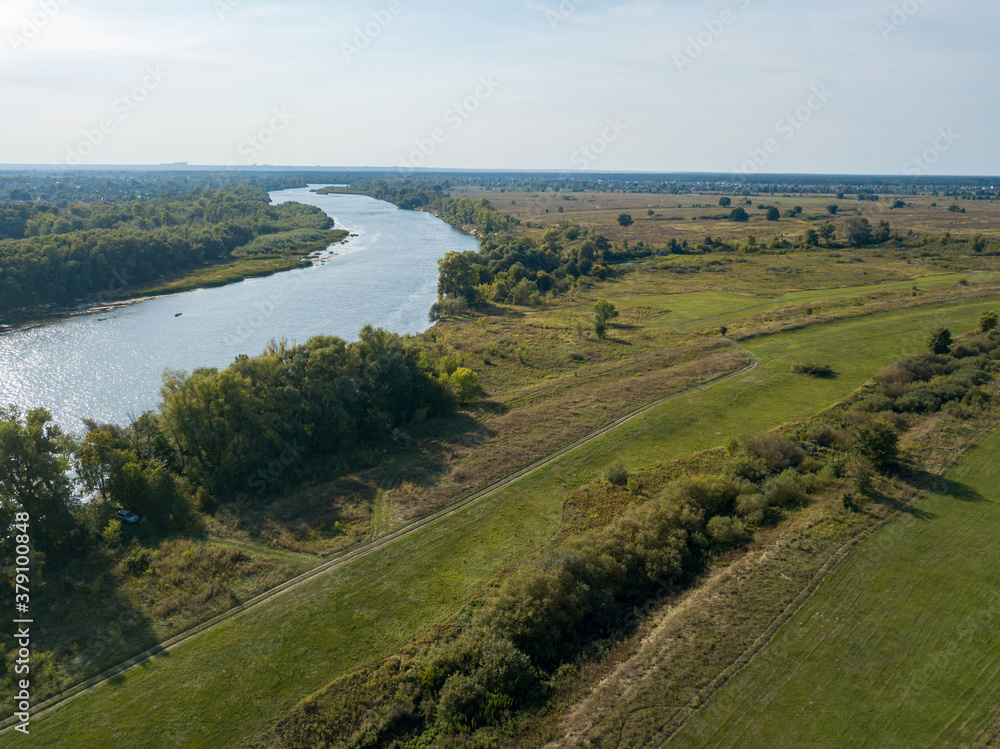 Naklejka premium Dirt road among green meadows. Summer sunny day. Aerial drone view.
