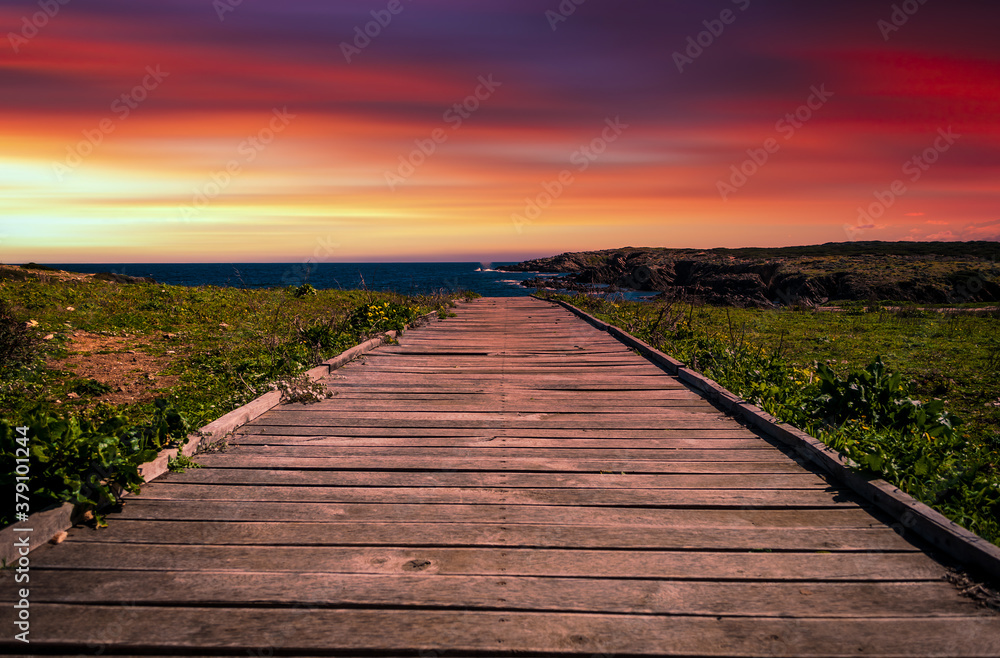wooden footbridge to the sea at sunset
