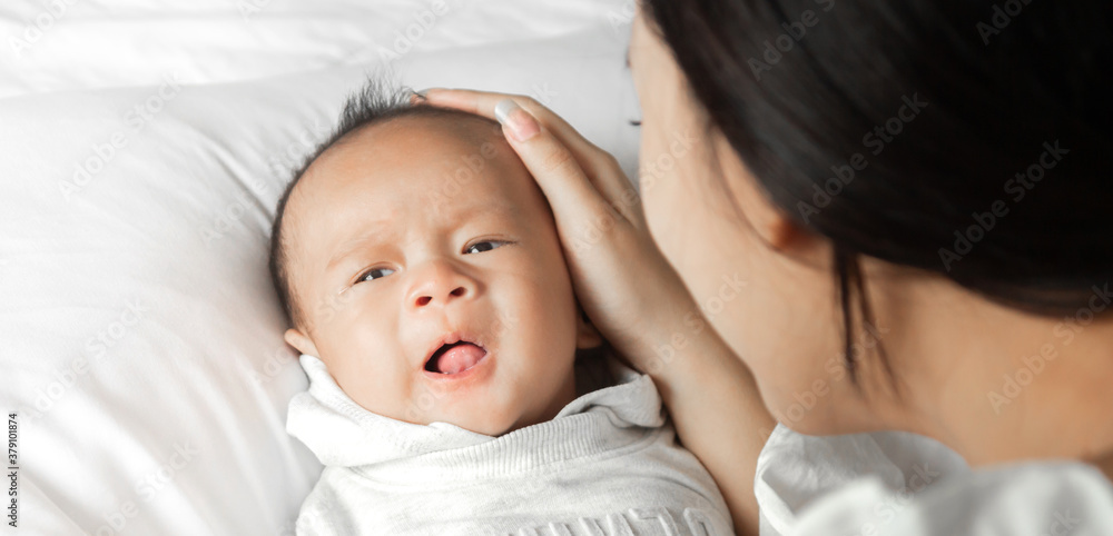 Portrait of enjoy happy love family asian mother playing with adorable little asian baby.Mom touching with cute son moments good time in a white bedroom.Love of family concept Portrait of enjoy happy love family asian mother playing with adorable little asian baby.Mom touching with cute son moments good time in a white bedroom.Love of family concept