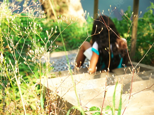 Photo with background metis girl seen from behind reading a book on a staircase outside at the water's edge photo